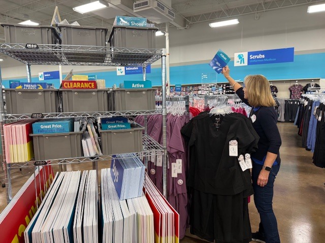 women hanging up sign in retail from custom made signage cart